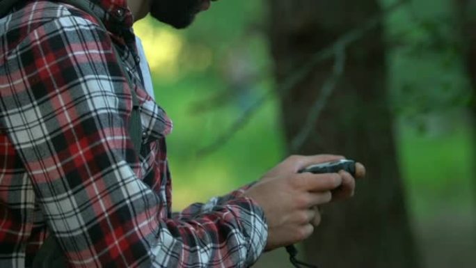 迷失的男性徒步旅行者在森林中使用指南针，试图找到正确的方式，旅游业