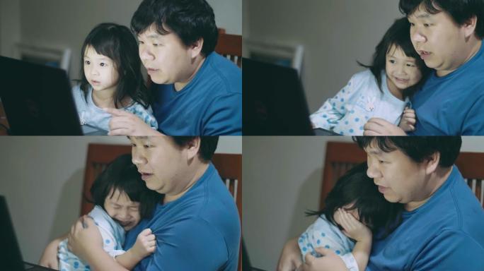 小女孩和她的父亲在家里用笔记本电脑看恐怖片