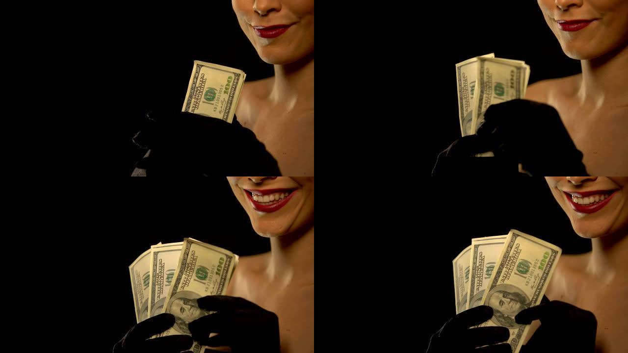微笑的女士向相机展示一束美元，孤立在黑色背景上