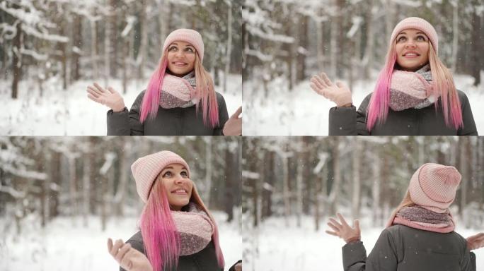 慢动作，冬天的女人在树林里看着雪落下，微笑着看着天空，直接对着镜头