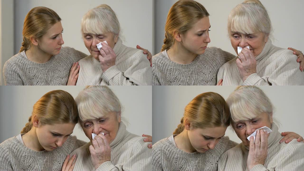 年轻的女士安慰不幸哭泣的奶奶遭受损失，在家庭中得到支持