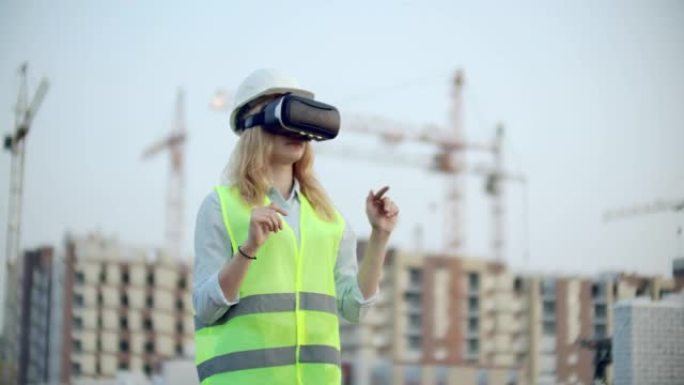 一位女检查员使用虚拟现实眼镜分析建筑商工作的肖像。一名戴着头盔和防护背心的妇女站在VR眼镜中并移动双