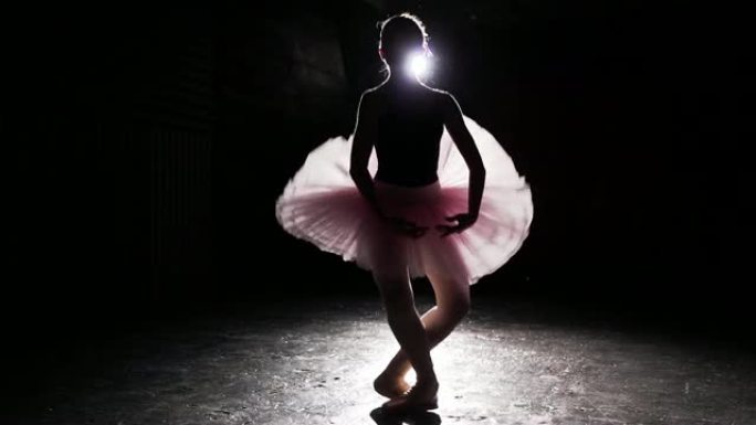 年轻芭蕾舞演员在黑色混凝土地板背景下的脚尖鞋上的美丽轮廓。芭蕾舞练习。女人展示经典芭蕾舞剧。芭蕾舞演