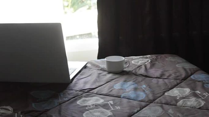 床上有笔记本电脑的咖啡杯