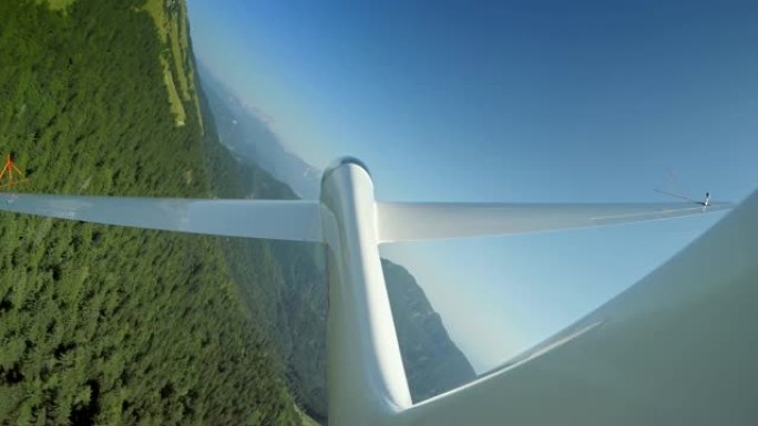 LD滑翔机在郁郁葱葱的绿色景观上方的阳光明媚的天空中循环