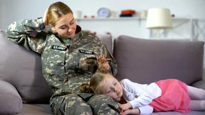 女儿睡在美国大兵妈妈的膝盖上，在家的沙发上休息