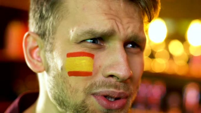 男球迷对国家足球队的失利感到不满，西班牙国旗在脸颊上