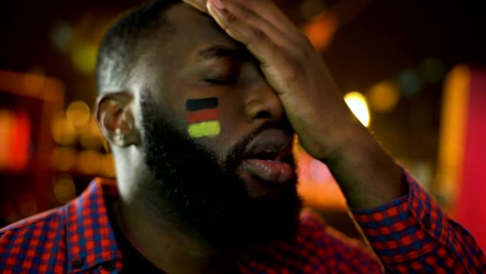 失望的德国足球迷，脸颊上的旗帜使面部表情，球队输了