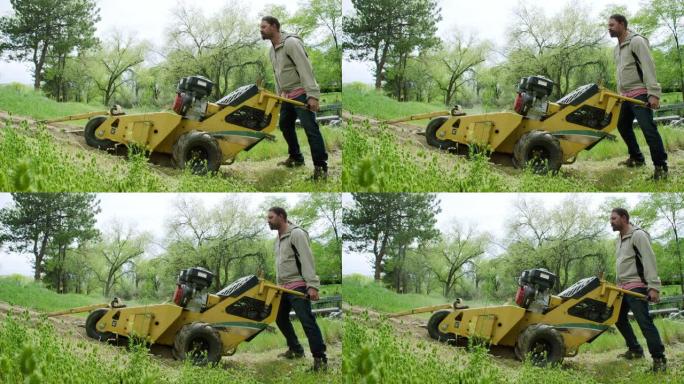 一个三十多岁的白人男子的慢动作镜头，用挖沟机在户外未耕种的区域将沟渠切入地面
