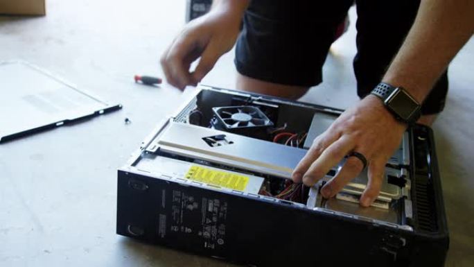 四十多岁的高加索人从车库地板上的计算机背面卸下硬件