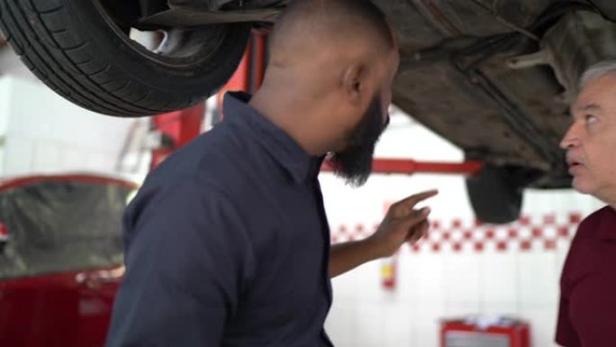 机械师在维修店向客户解释他的汽车缺陷