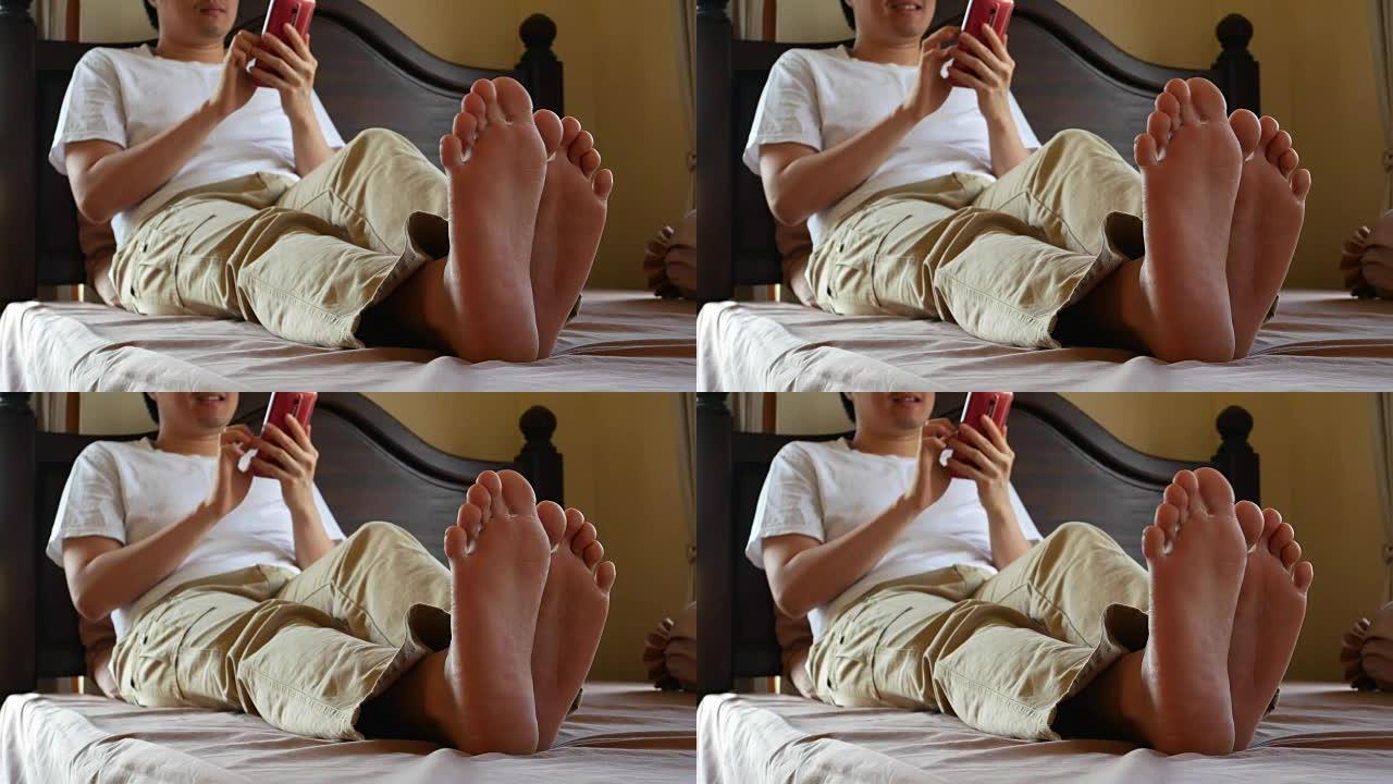 快乐男人在床上用手机-专注于男人的脚