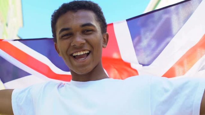 极为快乐的美国黑人少年挥舞着英国国旗，喜庆的心情