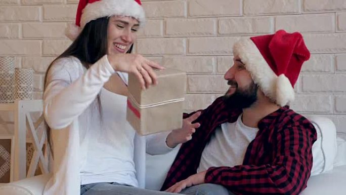 戴着圣诞老人帽子的幸福夫妇坐在椅子上送礼物