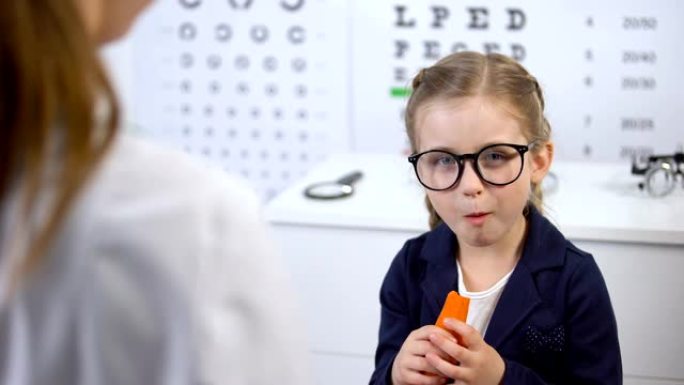戴眼镜的快乐孩子在医生的推荐下吃胡萝卜，β-胡萝卜素