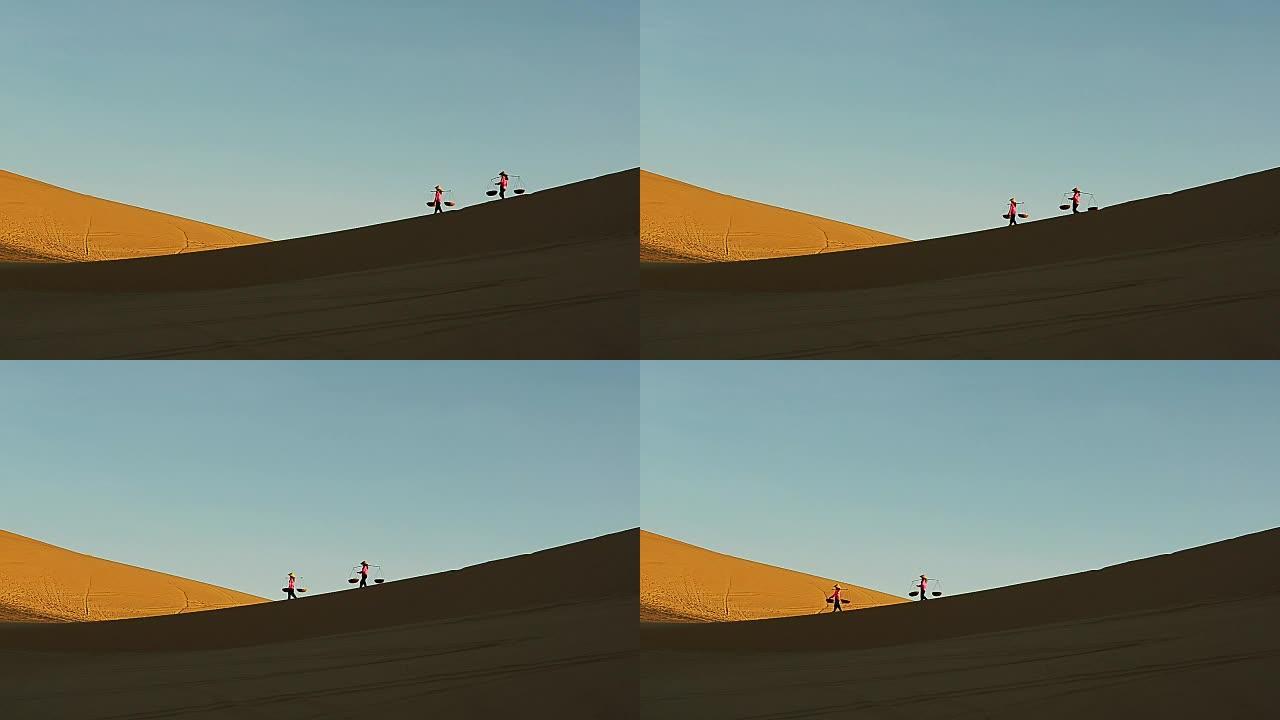 两名越南妇女带着柳条篮子在沙丘上行走