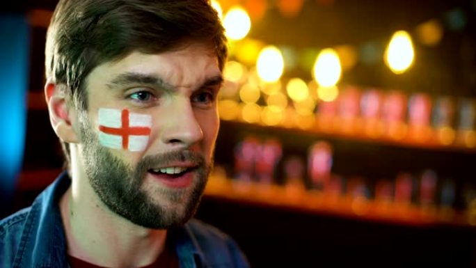 不悦的男足球迷，脸颊上挂着英国国旗，做出面部表情手势