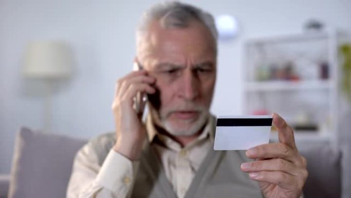恼怒的老人通过手机与银行支持服务谈论信用卡