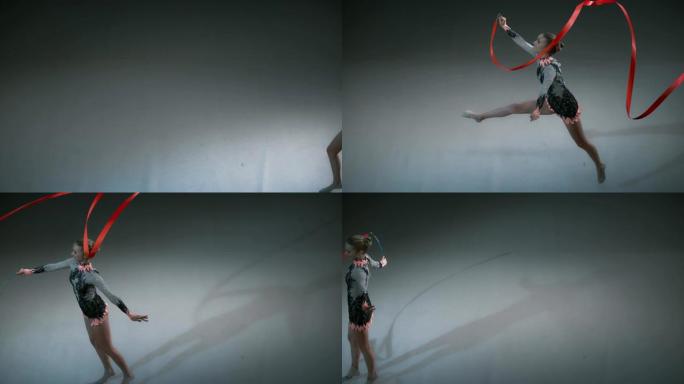 SLO MO艺术体操运动员旋转她的红丝带并进行了一次跳跃