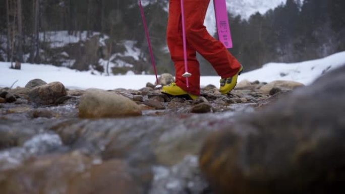 慢动作细节拍摄的滑雪者在雪地里用岩石和水过河的镜头