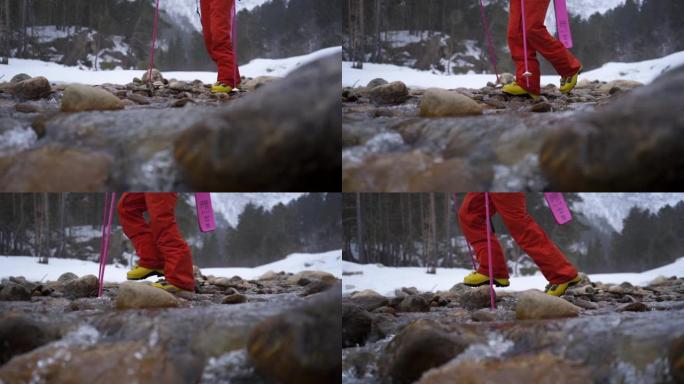 慢动作细节拍摄的滑雪者在雪地里用岩石和水过河的镜头