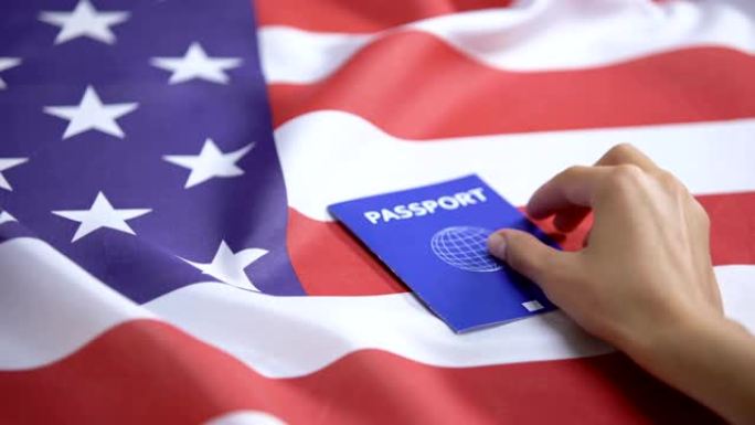 女性手将国际蓝色护照放在美国国旗上，签证申请人