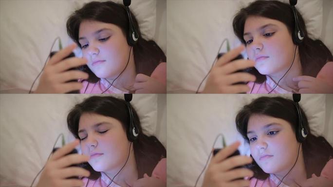 十几岁的女孩晚上在床上用耳机听音乐