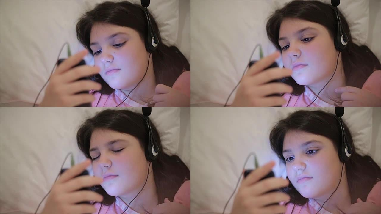十几岁的女孩晚上在床上用耳机听音乐