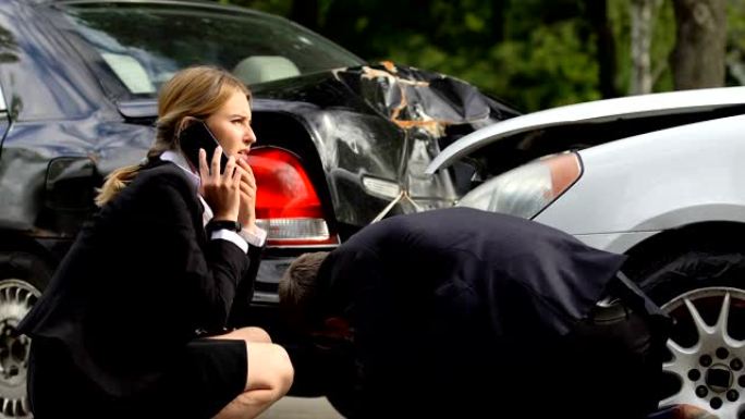 紧张的男人和女人打电话给警察，看上去被砸碎的汽车，交通相撞