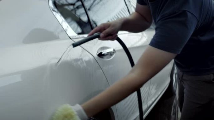 慢动作亚洲男人在房子里洗他的白色汽车。