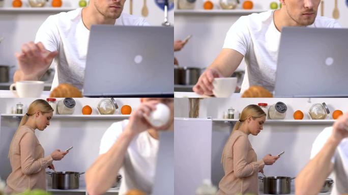 男子在笔记本电脑上喝咖啡，妻子在准备晚餐时用电话
