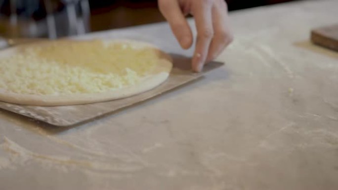 库克把生披萨放在锅铲特写上。烹饪披萨。