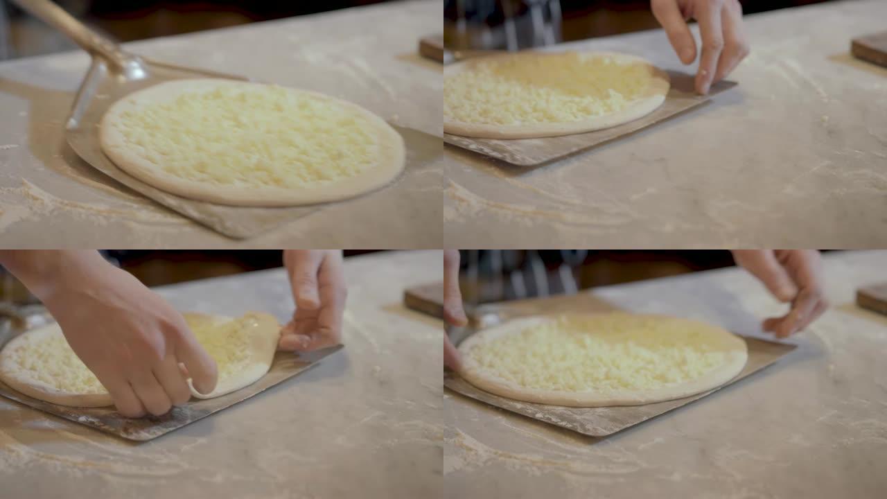 库克把生披萨放在锅铲特写上。烹饪披萨。