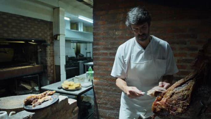 阿根廷厨师在Parrilla上切牛肉的手持照片