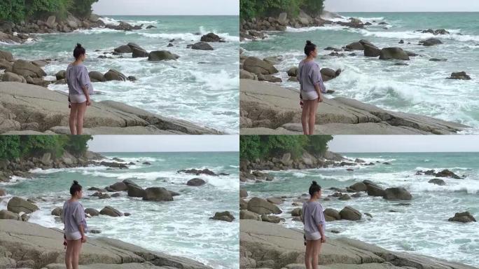4k: 岩石上的海滩上的女孩受到波浪打击