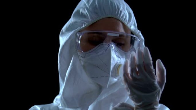 穿着防护服眼镜和呼吸器戴手套的女研究员