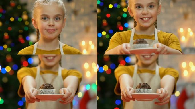围裙上的小女孩向相机展示纸杯蛋糕，以自制糕点为荣