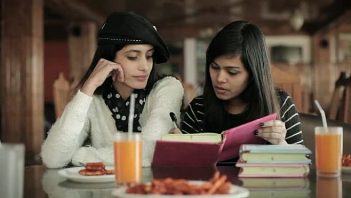 大学生朋友在餐厅一起学习和教学。