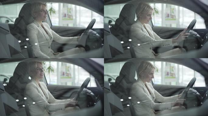 穿着优雅白色西装的白人成年女商人的肖像坐在汽车经销店的驾驶座上。快乐成功的女人触摸方向盘和微笑。陈列