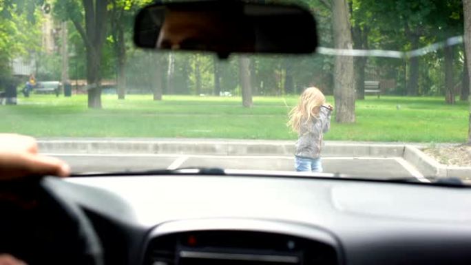 驾驶员在道路上玩耍的注意力不集中的孩子的前面停下来，父母拥抱孩子