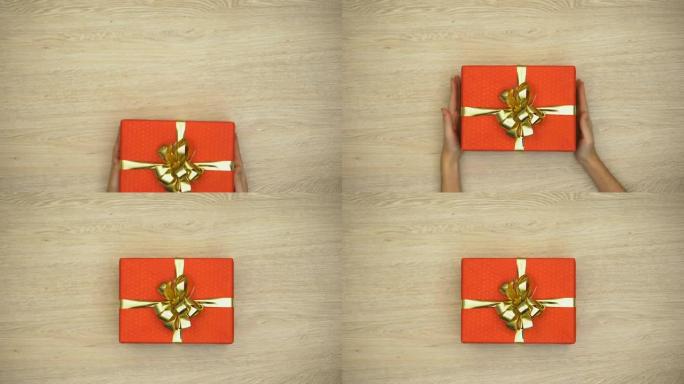 女人手把礼品盒放在木制背景上，节日庆典，顶视图
