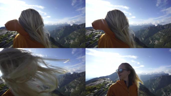 女性金发徒步旅行者在山顶上鞭打头发