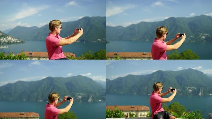 年轻人在山脉和湖泊的视线处用智能手机拍照