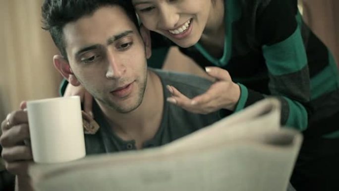 一对幸福浪漫的情侣在咖啡休息时间一起看报纸。
