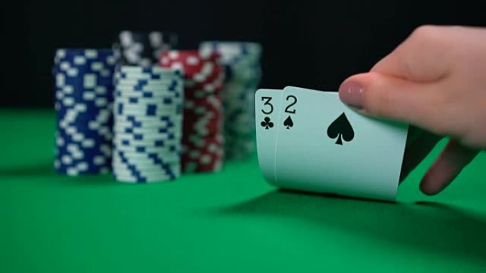 扑克游戏，玩家检查手，考虑赌注。卡片特写，德州扑克