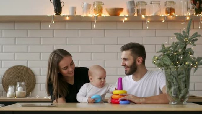 家庭，假期和人的概念-快乐的母亲，父亲和小女儿在生日聚会上玩ring pyramid婴儿玩具
