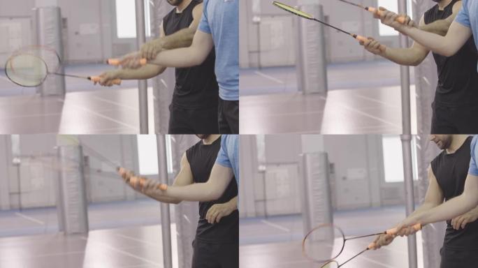 无法识别的运动员在羽毛球中练习手部运动的侧视图。两个白人男子手握球拍。室内运动游戏训练。