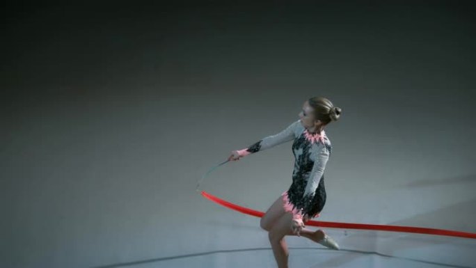 SLO MO艺术体操运动员在表演雄鹿飞跃时将她的红丝带旋转成一个大圆圈