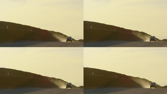 日落时分，一辆美国边境巡逻卡车沿着一条尘土飞扬的土路行驶，与墨西哥和美国之间的钢板条边界墙平行