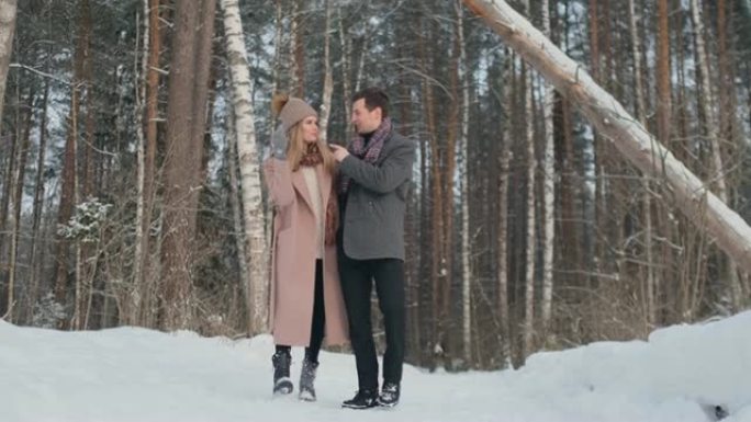 在冬日白雪皑皑的森林里，身着大衣、披巾的青年男女在散步、玩乐。相爱的情侣一起度过情人节